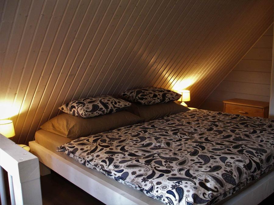 Podkrovní ložnice s dvoulůžkem a noční lampou
